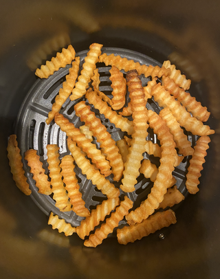 bild ovanifrån av matlagningskorgen på ninja air max xl air fryer som innehåller gyllenbruna crinkle frites