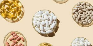 olika piller och kapslar, vitaminer och kosttillskott i petriskålar på beige bakgrund